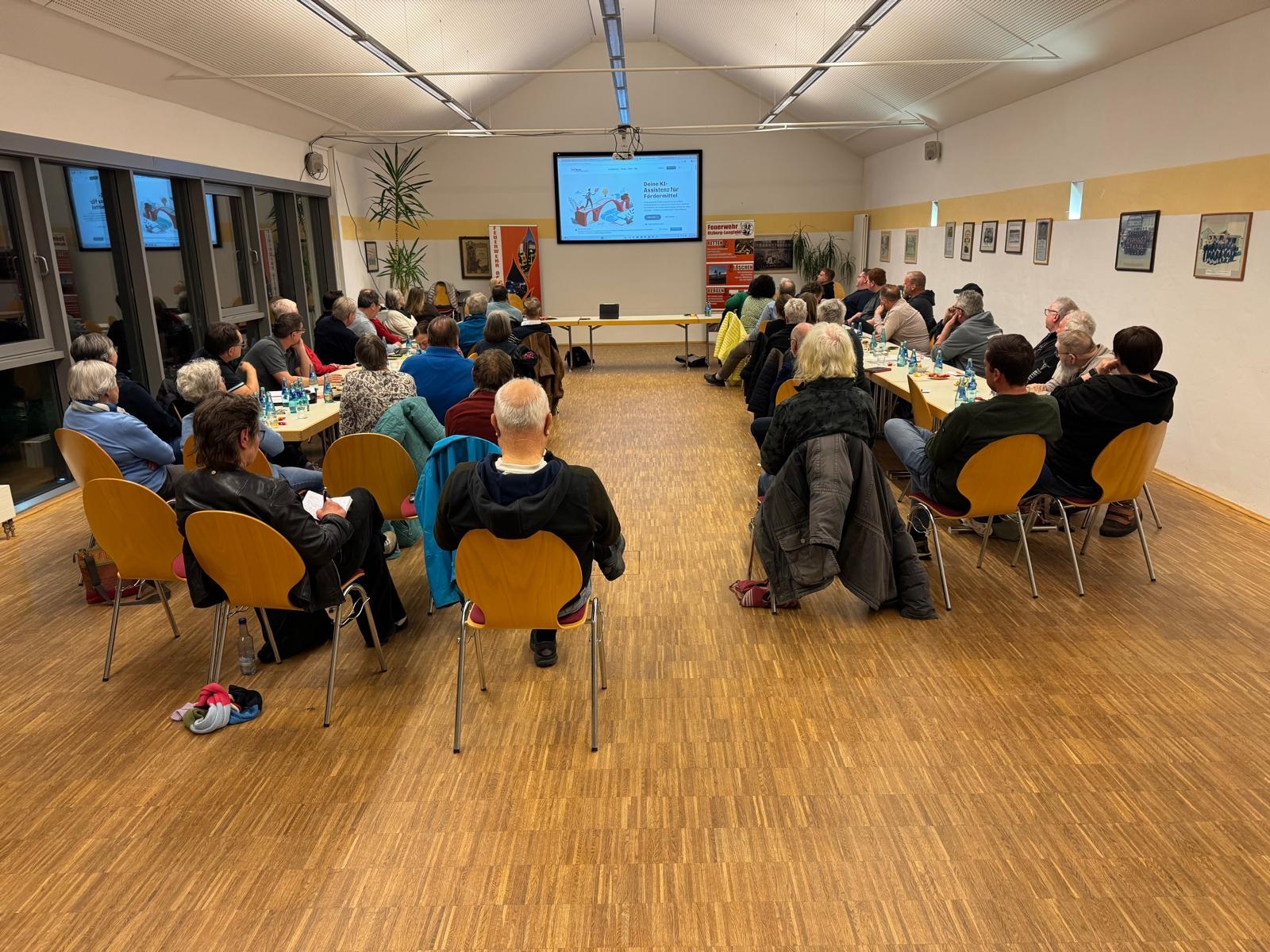 Personen, die auf Stühle sitzen und auf eine Leinwand schauen