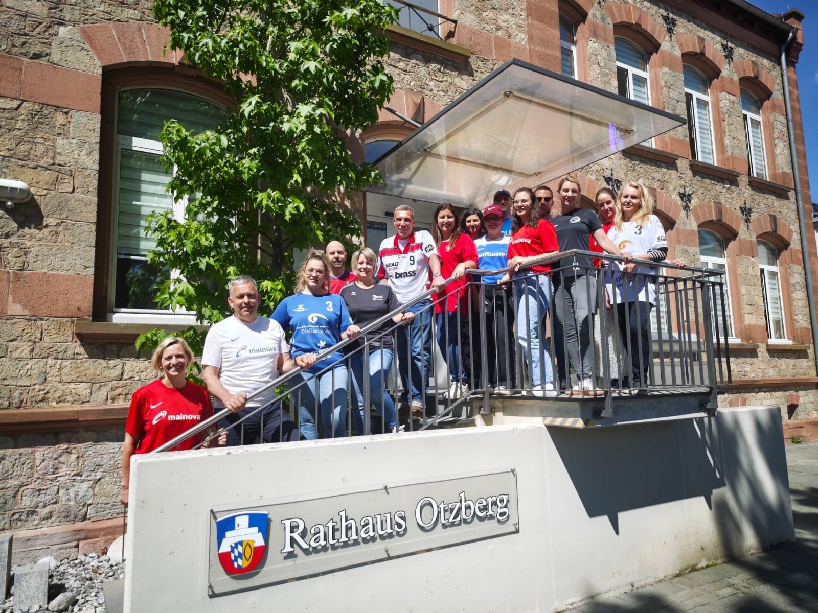 Mitarbeiter des Rathauses stehen im Trikot auf der Eingangstreppe zum Rathaus